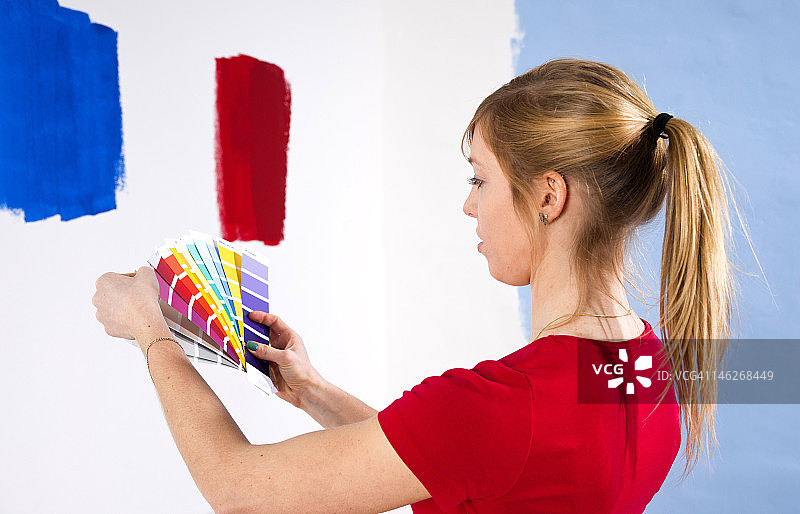 一名年轻女子拿着颜色样本站在墙上图片素材