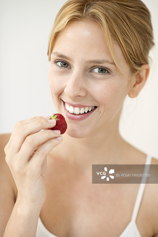 年轻女子吃草莓，肖像图片素材