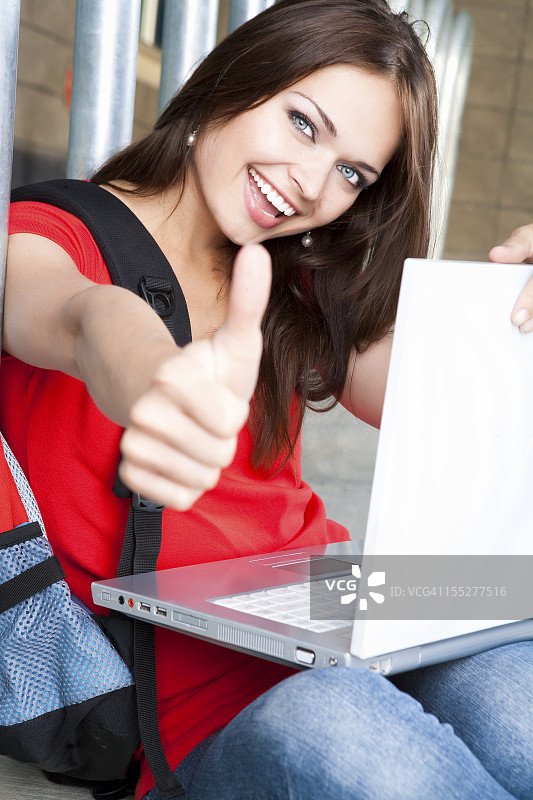 微笑的女性和她的笔记本电脑图片素材
