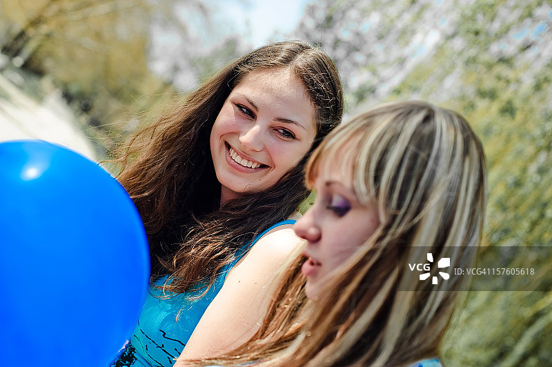 两个带着蓝色气球微笑的年轻女孩图片素材