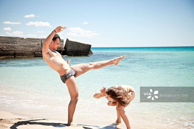 年轻的夫妇在海滩上玩的卡波耶拉舞图片素材