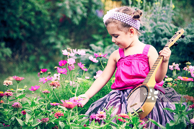 可爱的小女孩与古尤克里里班卓琴摘花图片素材