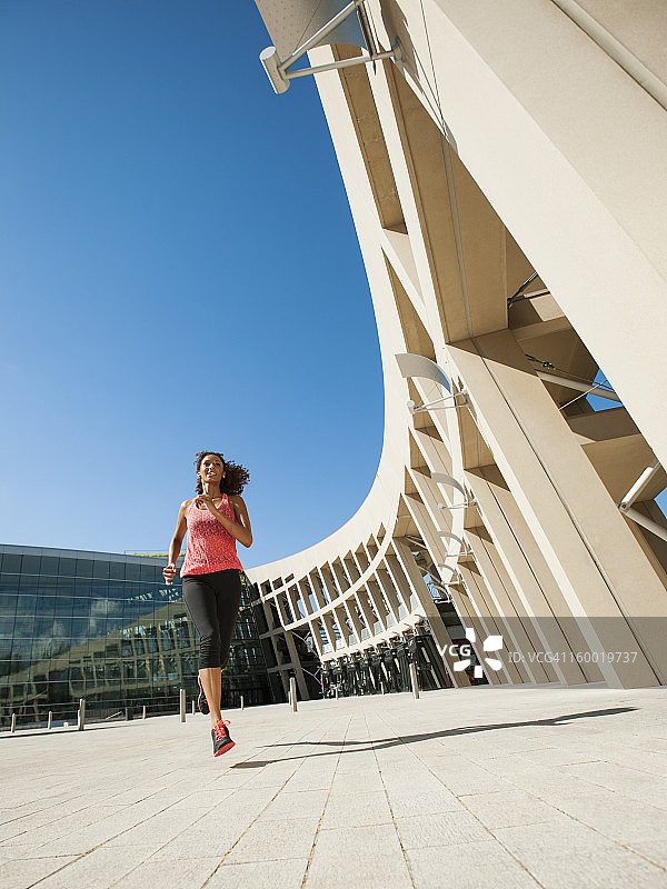 美国，犹他州，盐湖城，年轻女子沿着现代建筑慢跑图片素材