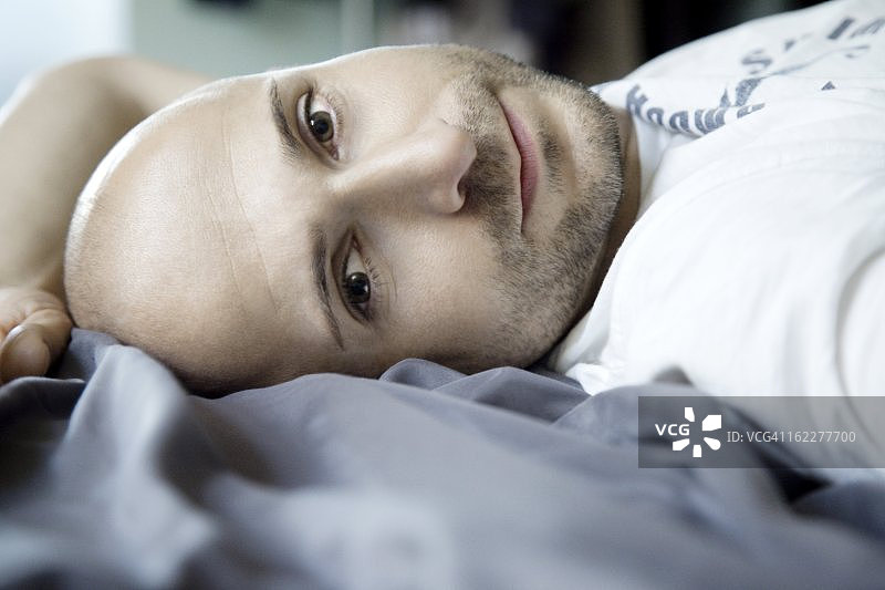 留着设计师设计的胡茬的男人躺在床上图片素材