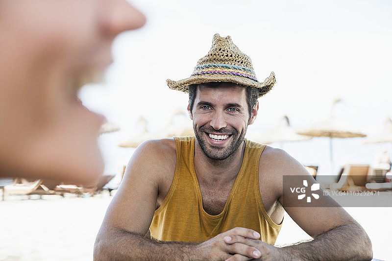 西班牙，中年夫妇坐在海滩上，面带微笑图片素材