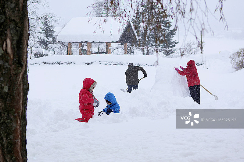 一家人在花园里堆雪人。图片素材