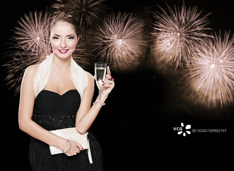 新年的女人拿着香槟对抗烟花图片素材