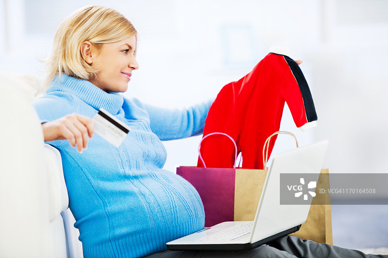 孕妇使用信用卡网上购物。图片素材