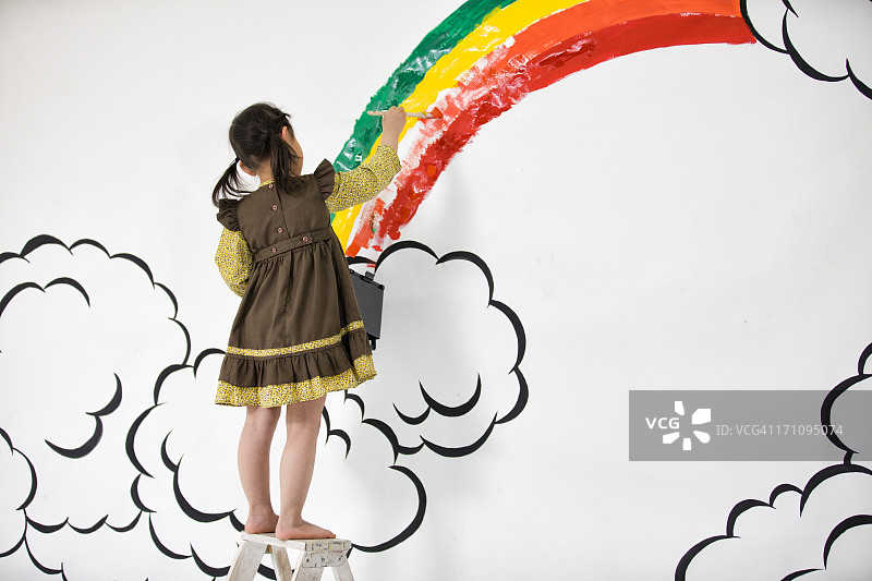 女孩在墙上画彩虹图片素材