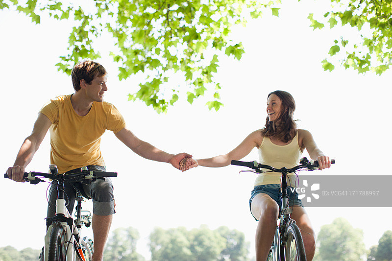 夫妇骑着自行车，手牵着手图片素材