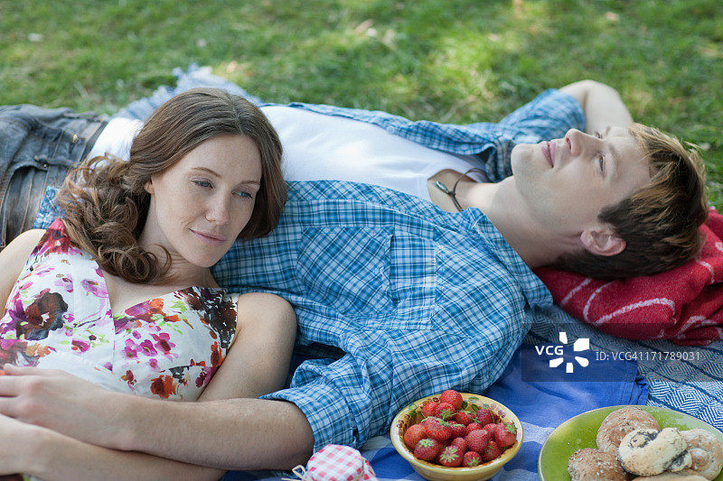 一对情侣在野餐，躺在草地上图片素材