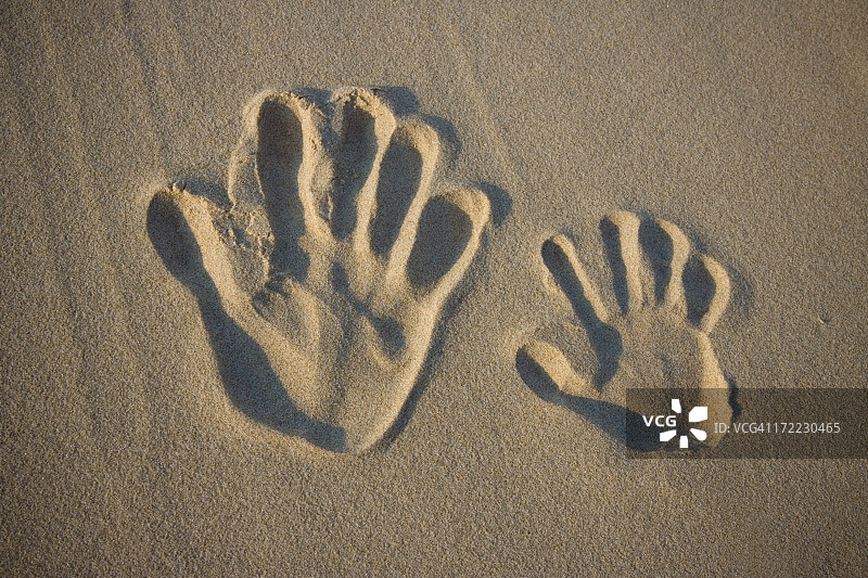 一只大手和一只小手在沙子里留下的印记图片素材