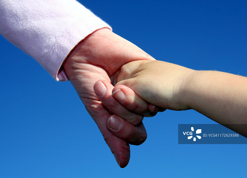 母亲和年幼的儿子牵着手在蓝色的背景图片素材