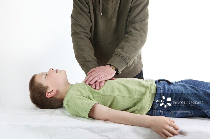 一个男人在给一个小男孩做心肺复苏术图片素材