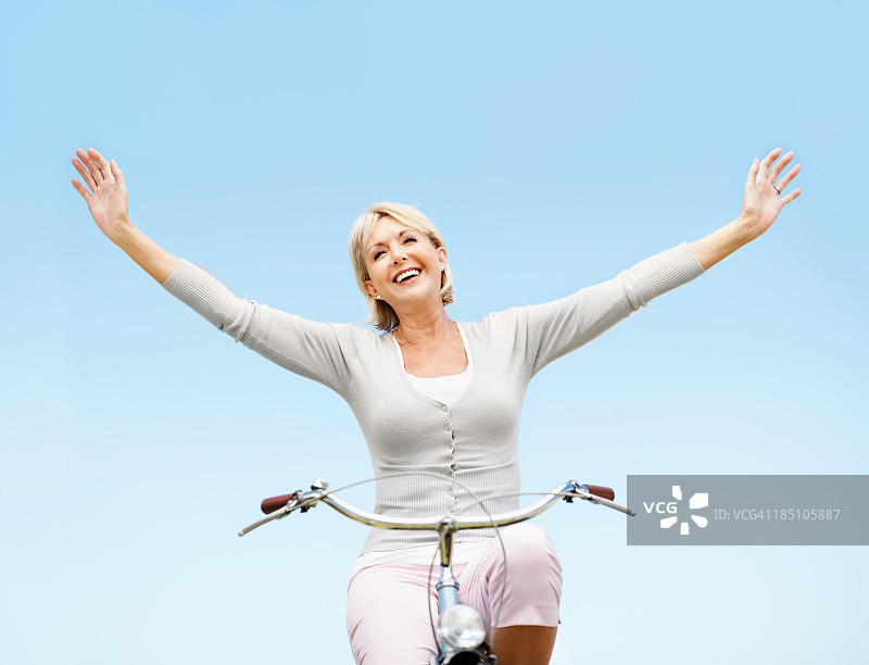 成熟的女人在自行车上伸开双臂图片素材