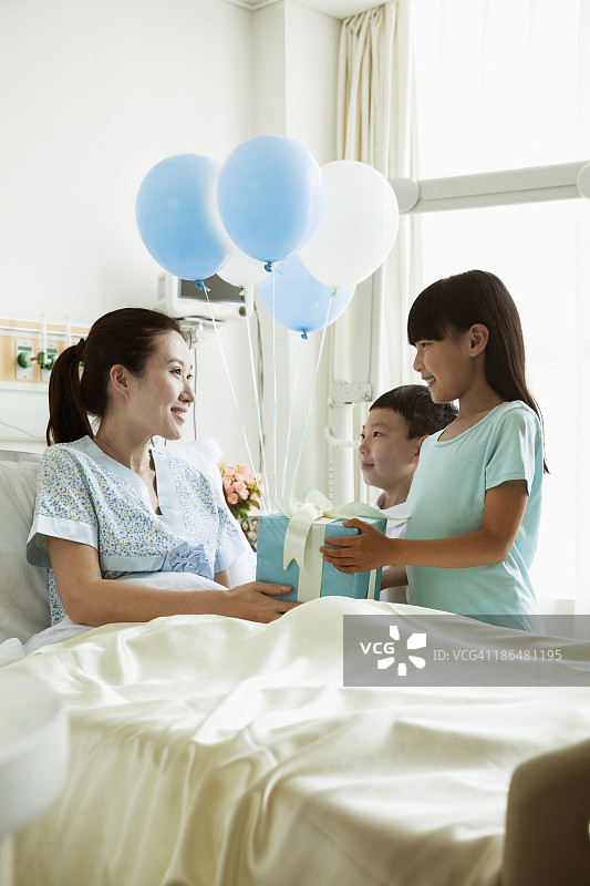 女孩和男孩去医院探望他们的母亲，赠送礼物和气球图片素材