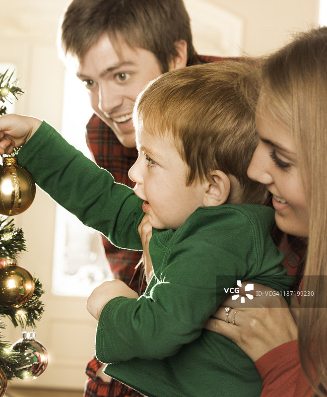 小男孩和爸爸妈妈一起装饰圣诞树图片素材