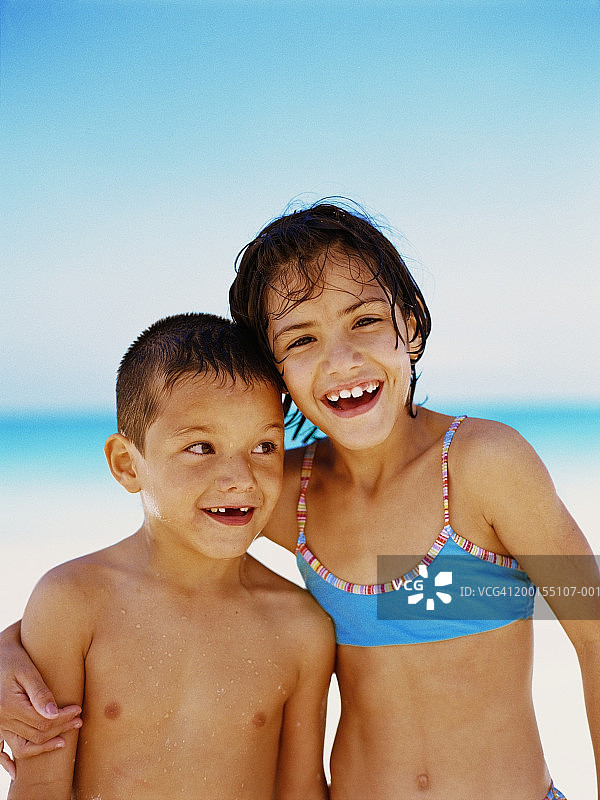 弟弟和妹妹(6-8)在海滩上，微笑着，画像图片素材