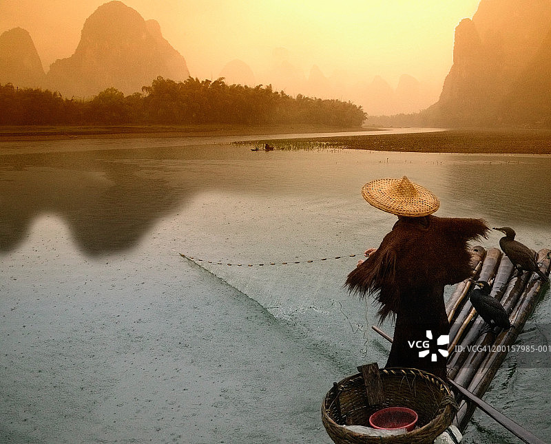 中国，广西，阳朔，渔民在竹筏上撒网，拂晓图片素材