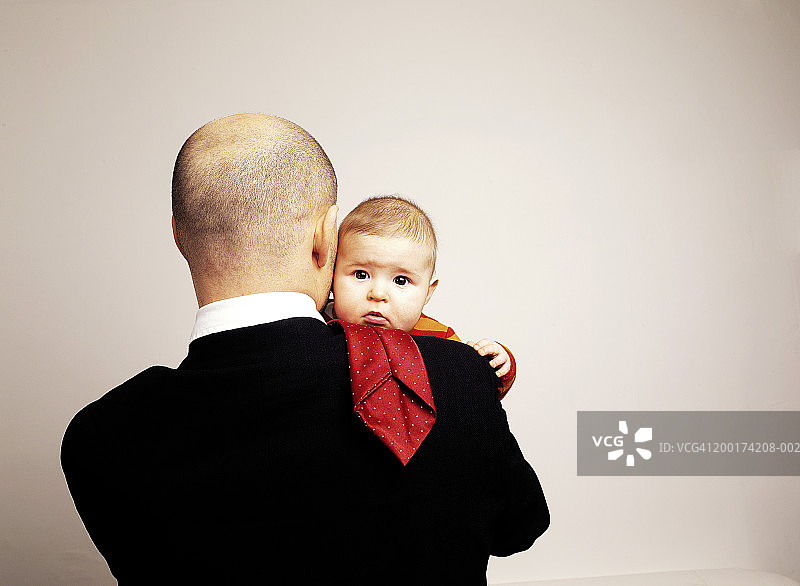 父亲抱着女婴(6-9个月)，后视镜中的男子图片素材