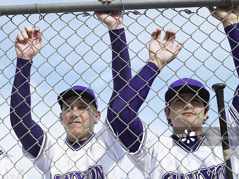在围栏附近的青少年(16-18岁)棒球运动员图片素材