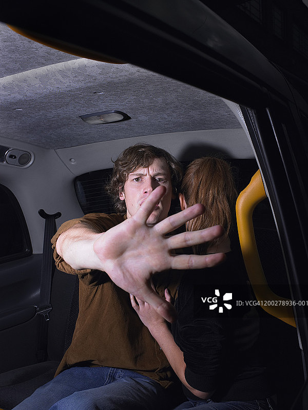 一对夫妇在出租车里，男人用手遮住窗户，肖像图片素材