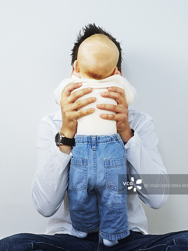父亲抱着婴儿儿子(3-6个月)，男孩的后视图图片素材