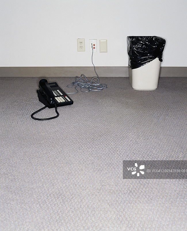 垃圾桶和电话在空办公室的地板上图片素材