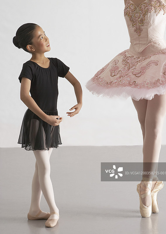 女孩(8-10)微笑着看着舞蹈课上的芭蕾舞老师图片素材