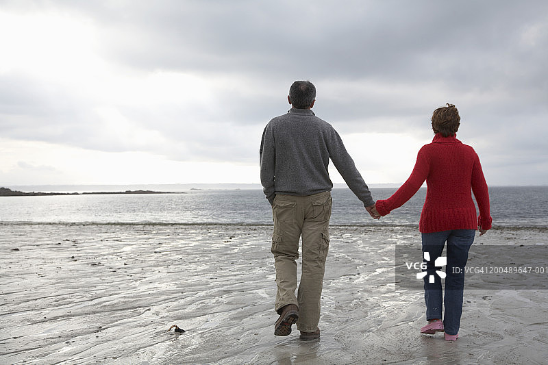 成熟的情侣手牵着手在沙滩上散步，后视镜图片素材