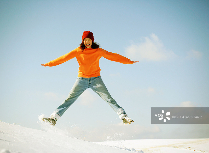 快乐的女人在雪中跳跃图片素材
