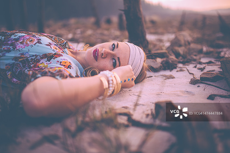 穿着复古服饰，戴着珠宝，站在沙地上的波西米亚女孩图片素材