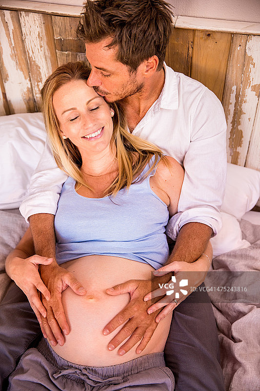 男人亲吻他怀孕的妻子，并抱着她的肚子图片素材