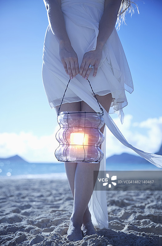 白种女人提着灯笼在海滩上图片素材