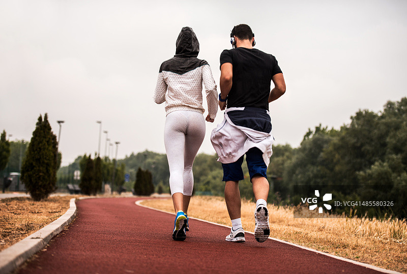 一对夫妇在跑道上一起慢跑的后视图。图片素材