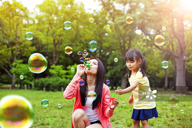 妈妈和女儿在公园和肥皂泡玩得开心图片素材