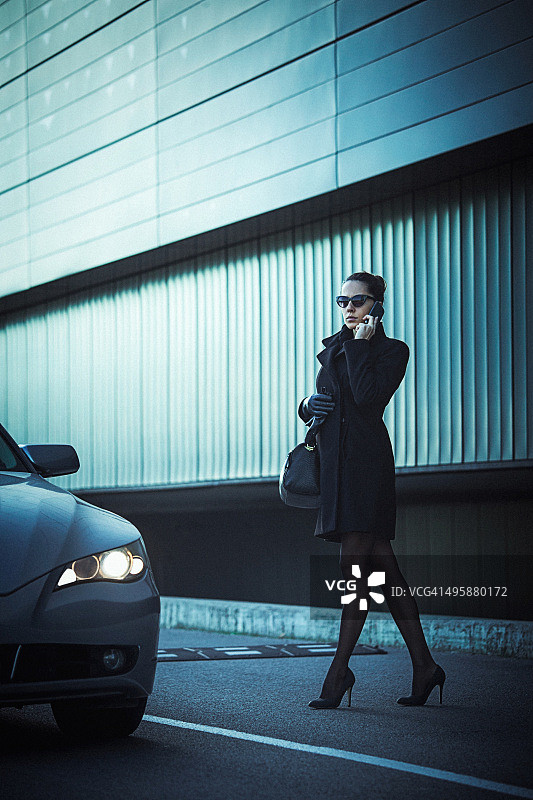 优雅的女人使用手机的特写，在车旁边图片素材