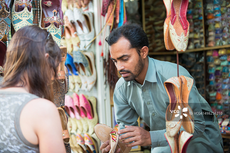 阿联酋迪拜，一名售货员在露天市场向一位女士展示鞋子图片素材