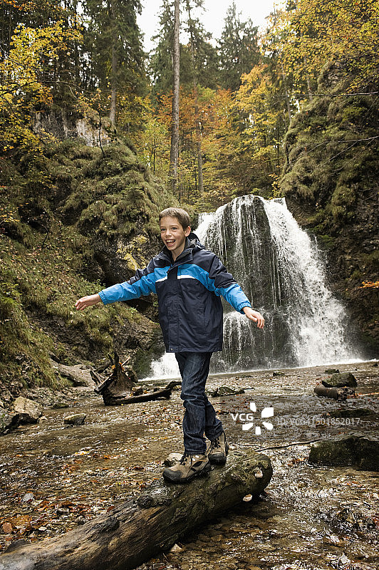 在欧洲德国巴伐利亚的森林里，一个男孩在树干上行走图片素材
