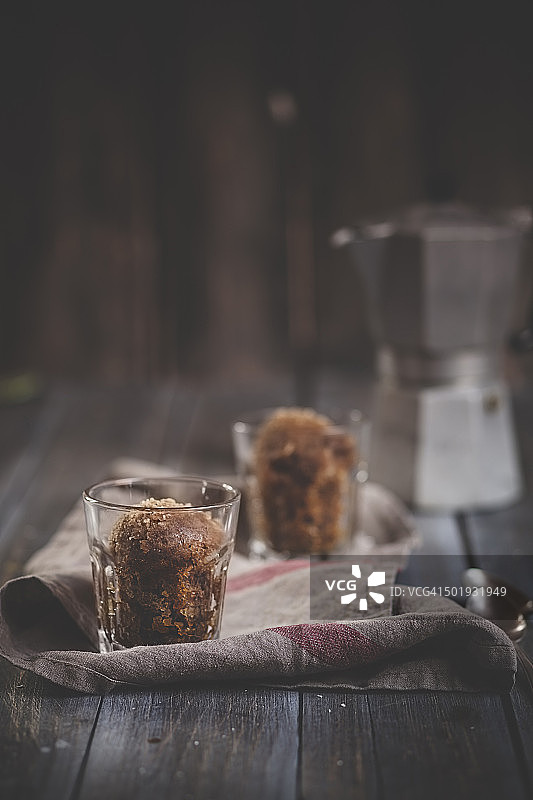 两杯格兰尼塔咖啡，厨房毛巾和浓咖啡罐放在深色木头上图片素材