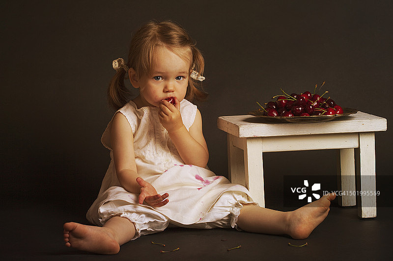 小女孩穿着白色复古裙吃樱桃图片素材