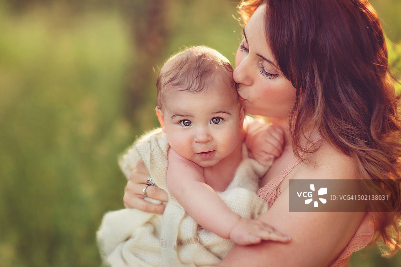 美丽的女人亲吻她孩子的太阳穴图片素材
