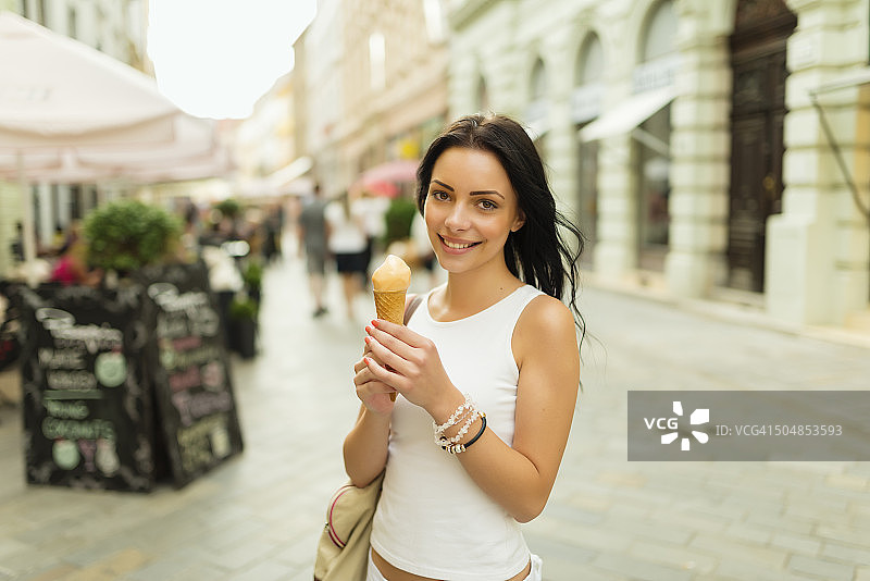 美丽的女孩在街上吃冰淇淋图片素材