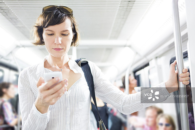 地铁里拿着智能手机的女人图片素材