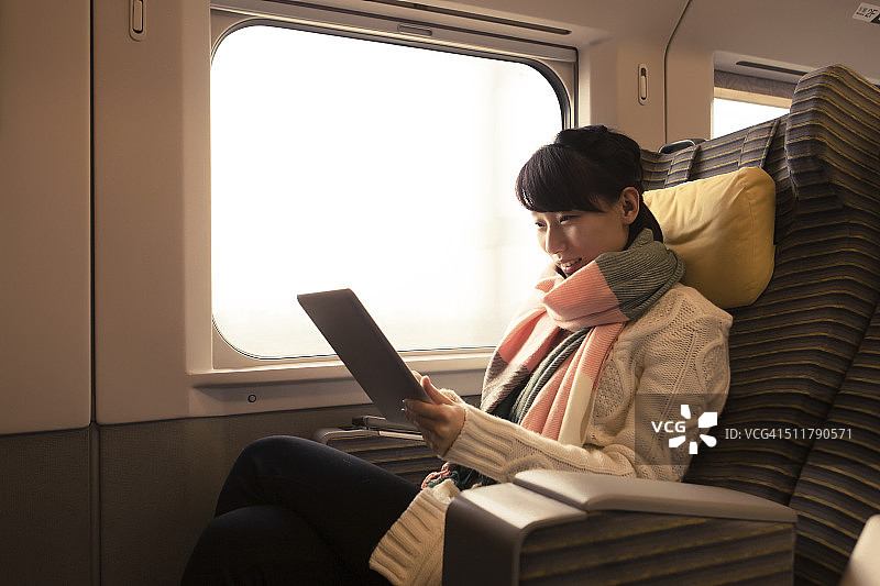 一名年轻女子在火车上使用平板电脑图片素材