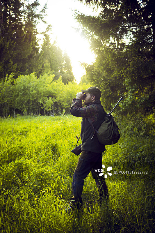 猎人在森林里用双筒望远镜观察距离图片素材