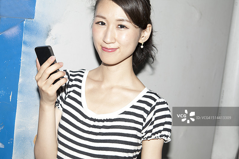 年轻的日本女子用手机，微笑着图片素材