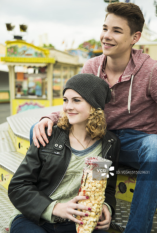 快乐的青少年夫妇的肖像与爆米花在游乐场图片素材