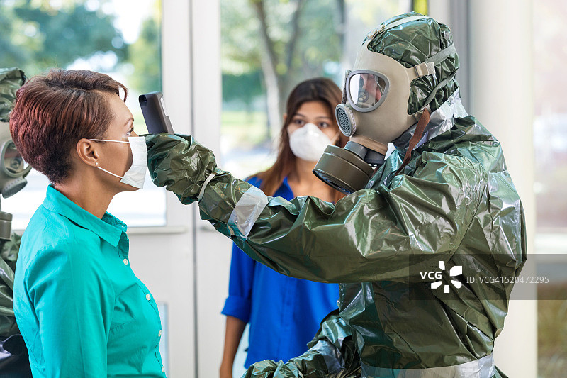在传染病爆发期间，身着防护服的医生正在检查一位妇女图片素材