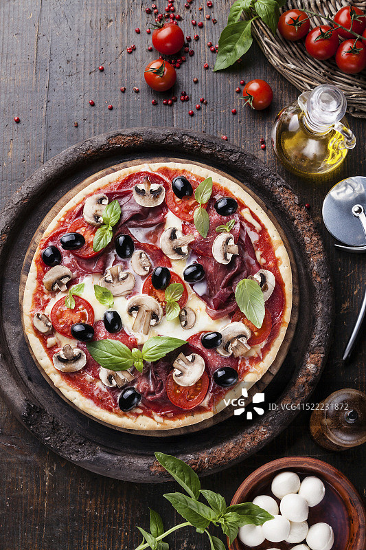 木桌上有意大利香肠、蘑菇和橄榄的意大利披萨图片素材